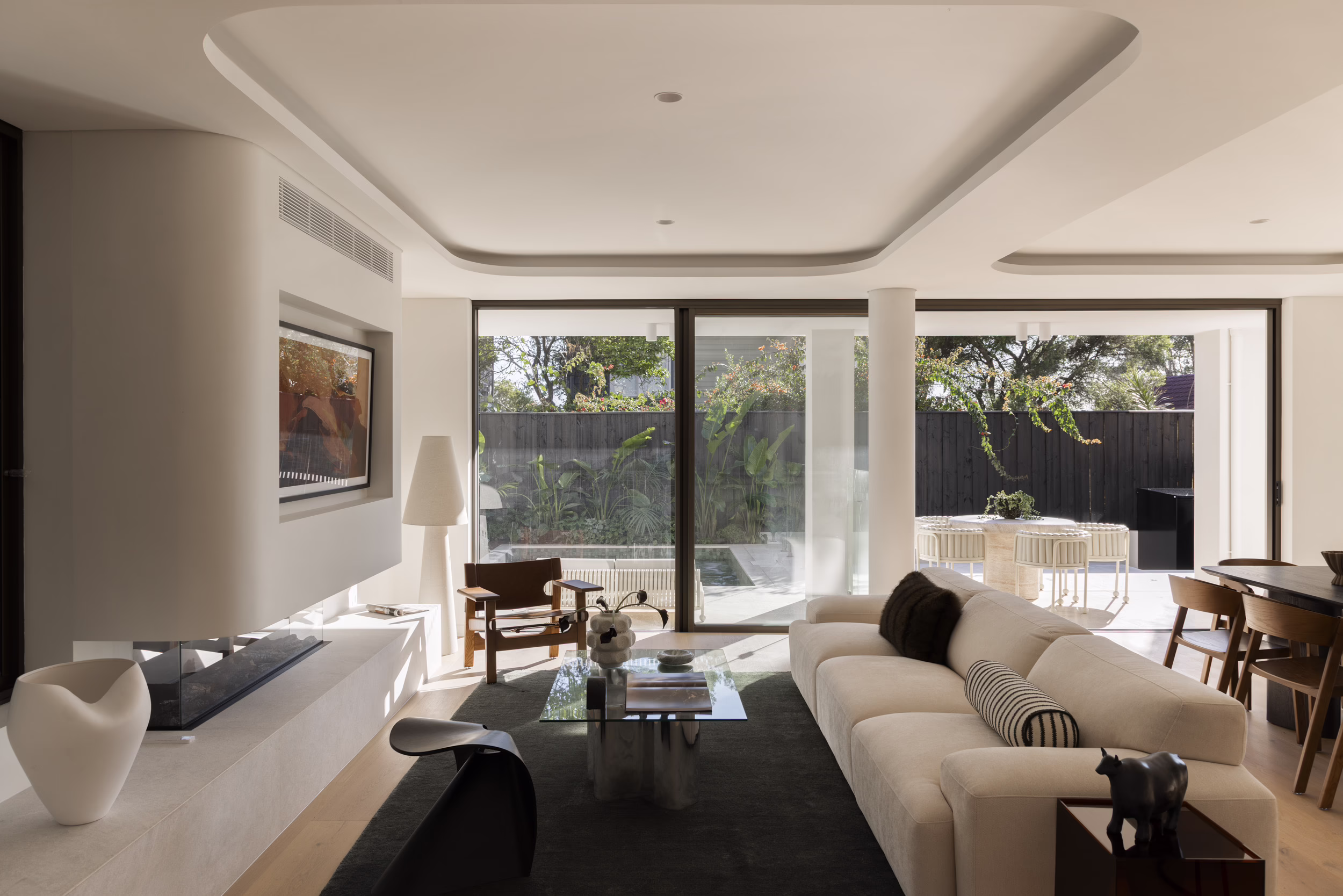 Living room at Edward Street House, with a curved ceiling recess and sliding doors opening to the poolside terrace