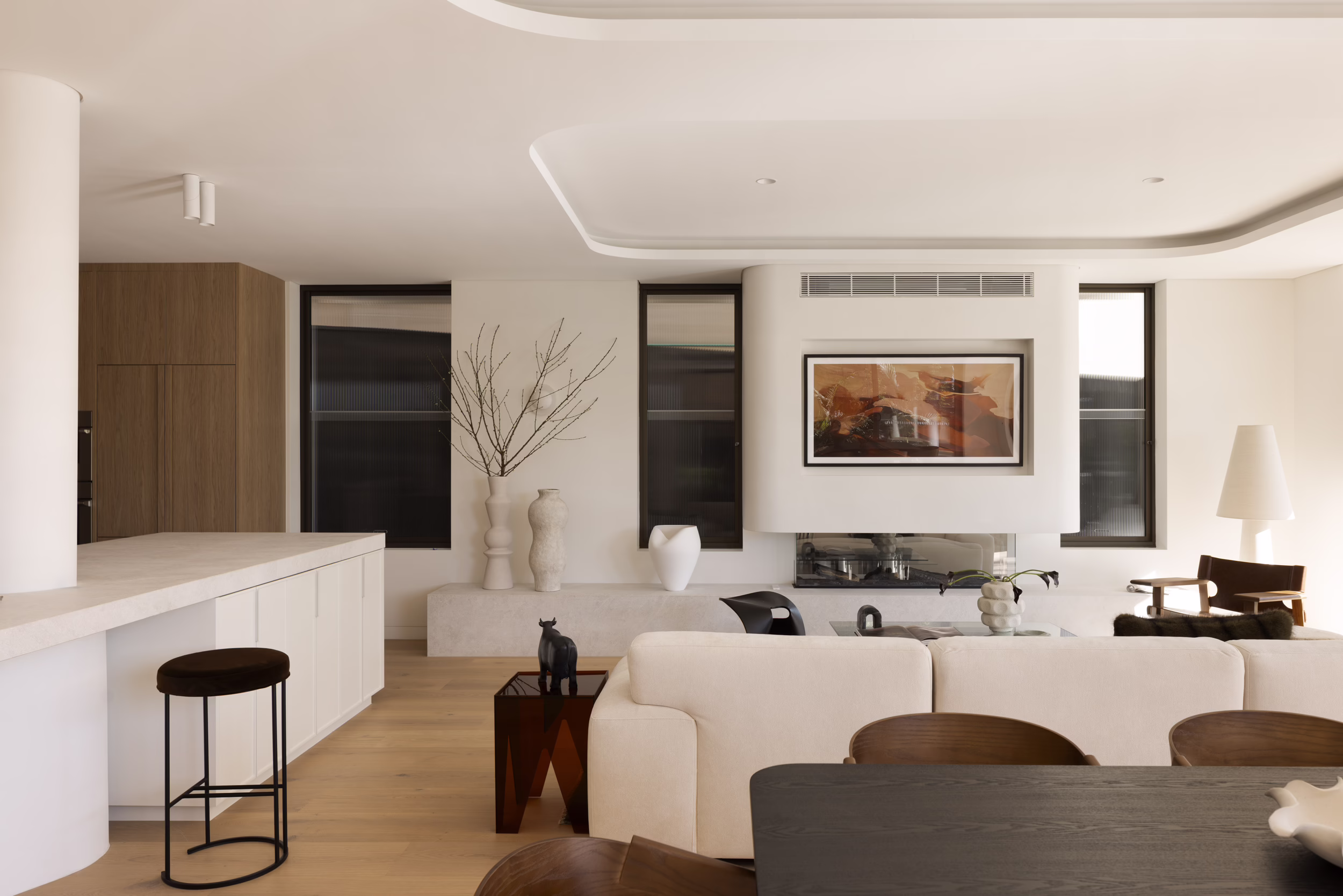 Edward Street House living area with a pale sofa, low fireplace, timber floor and rounded kitchen island